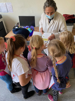 Künstlerin Grit Wendelberger zeigt einer Gruppe Kinder eine Abbildung in einem Buch